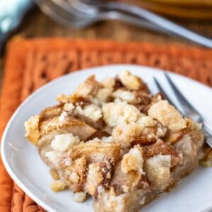 Piece of apple crumb bar on a white plate with a silver fork.