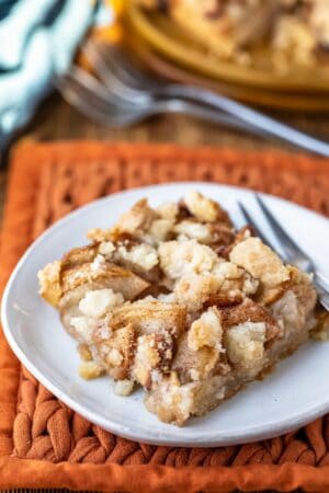 Piece of apple crumb bar on a white plate with a silver fork.