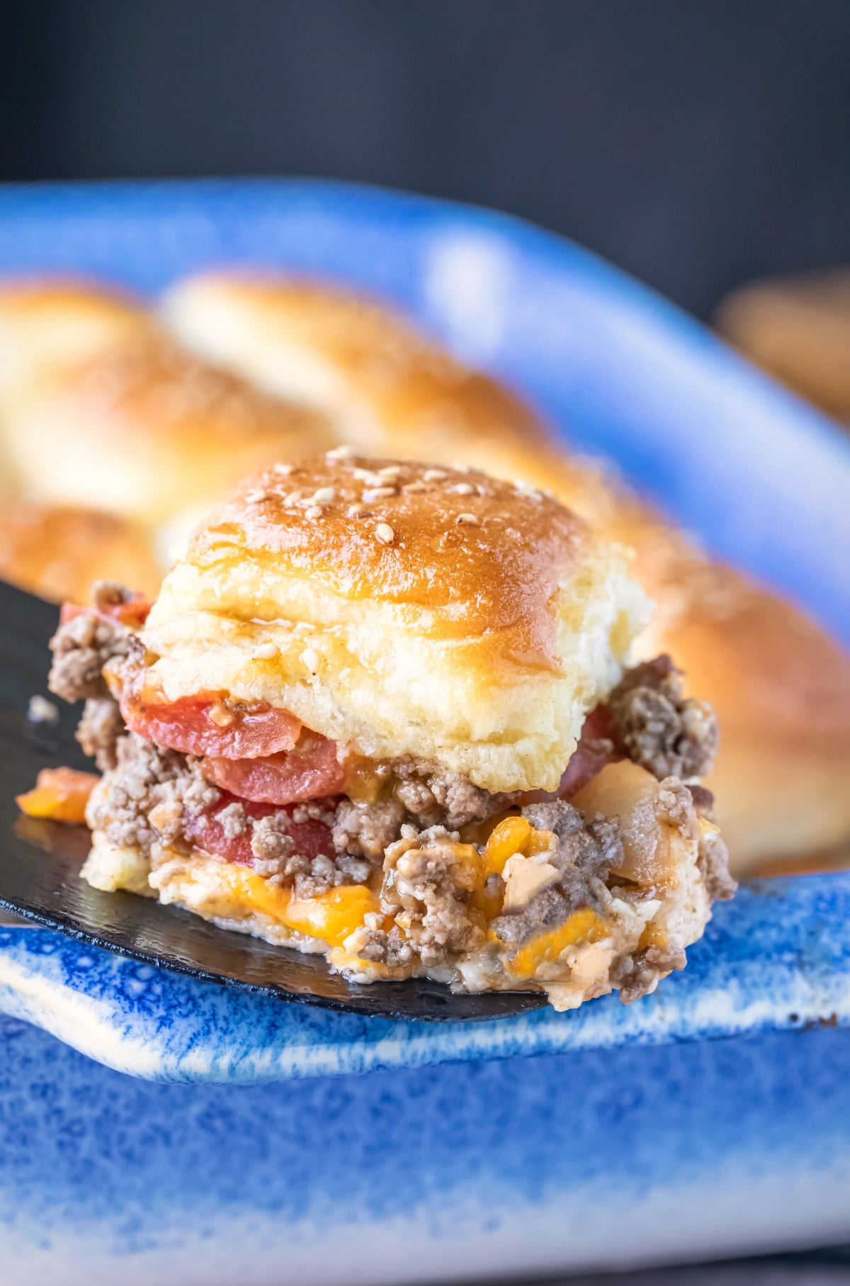 Black spatula holding a cheeseburger slider