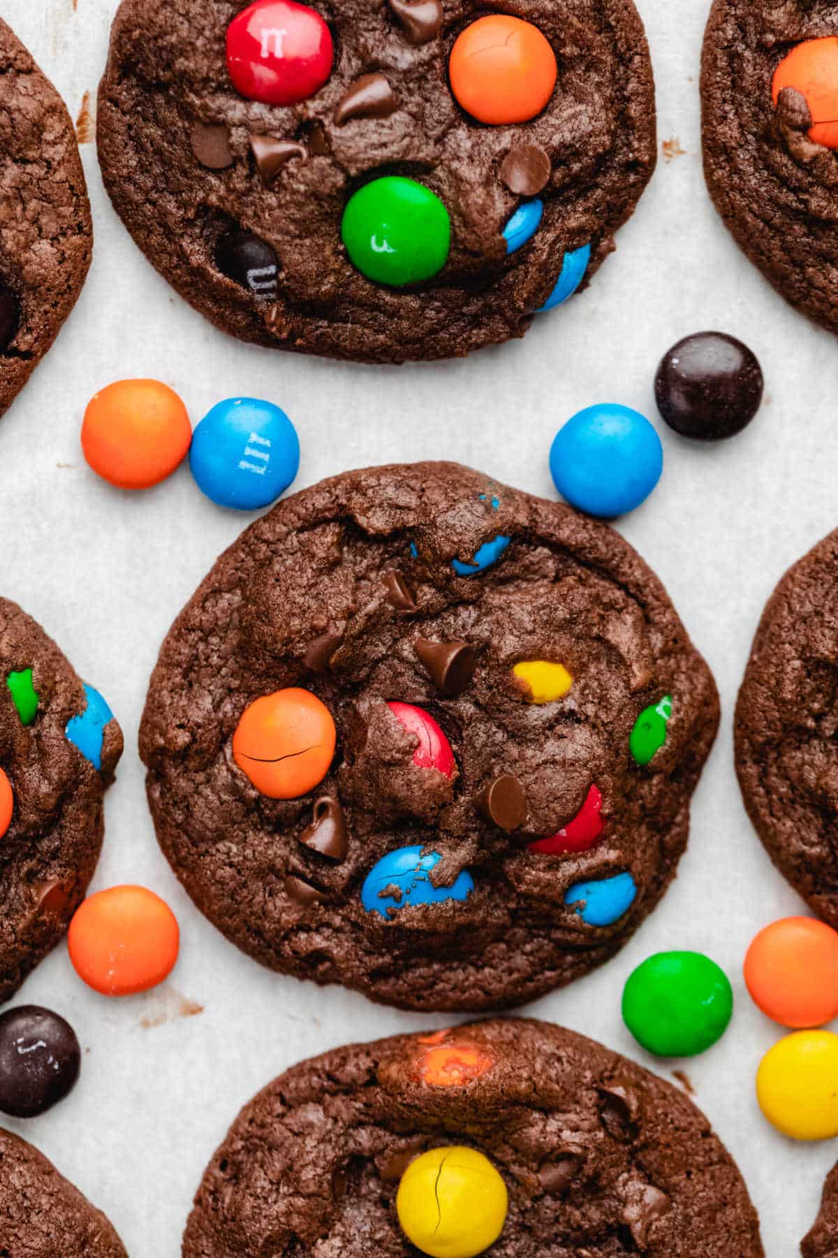 Rows of chocolate M&M cookies on parchment paper.