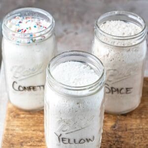 Three jars of homemade cake mix on a wooden cutting board.