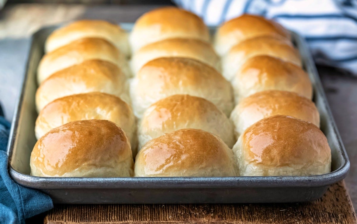 Silver baking tray of one hour dinner rolls on a wooden cutting board