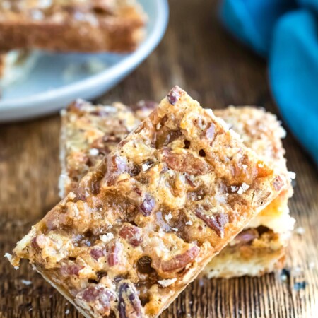 Toffee pecan pie bar leaning up against stack of bars