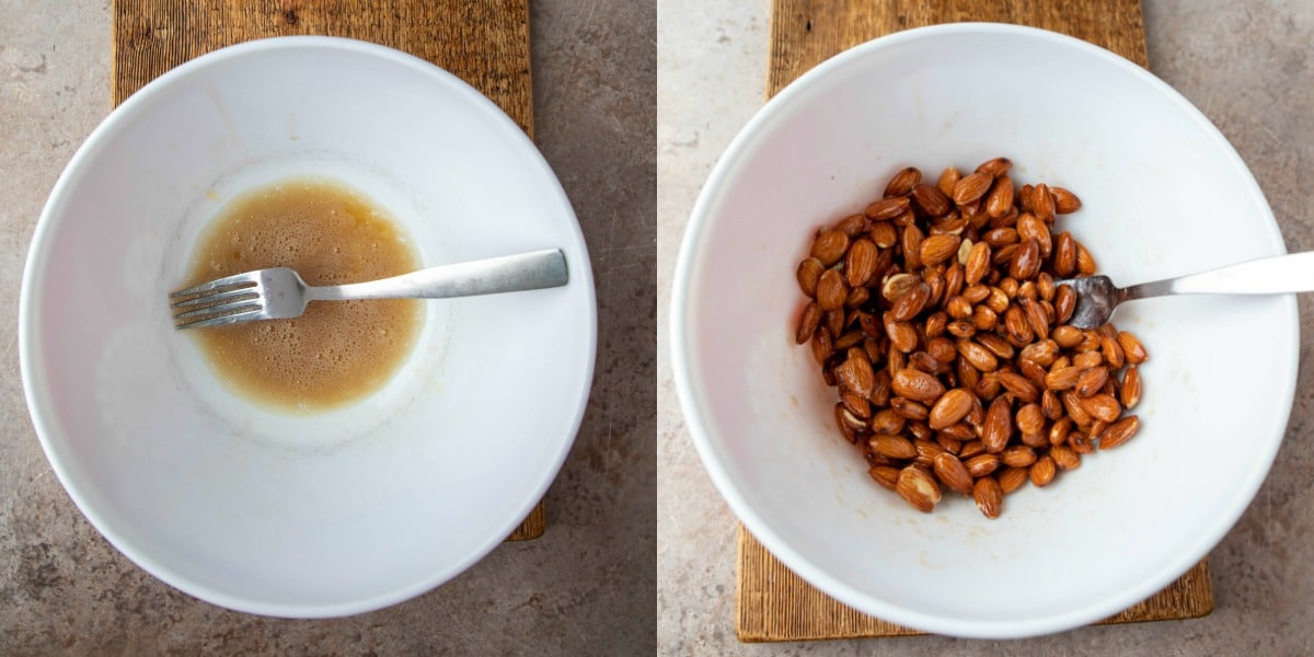 Almonds coated in beaten egg white mixture in a white mixing bowl