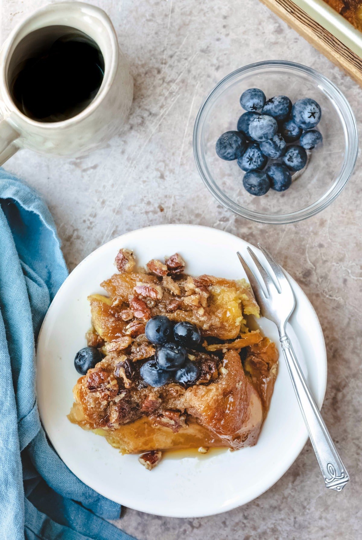 Plate of praline french toast next to a glass dish with blueberries