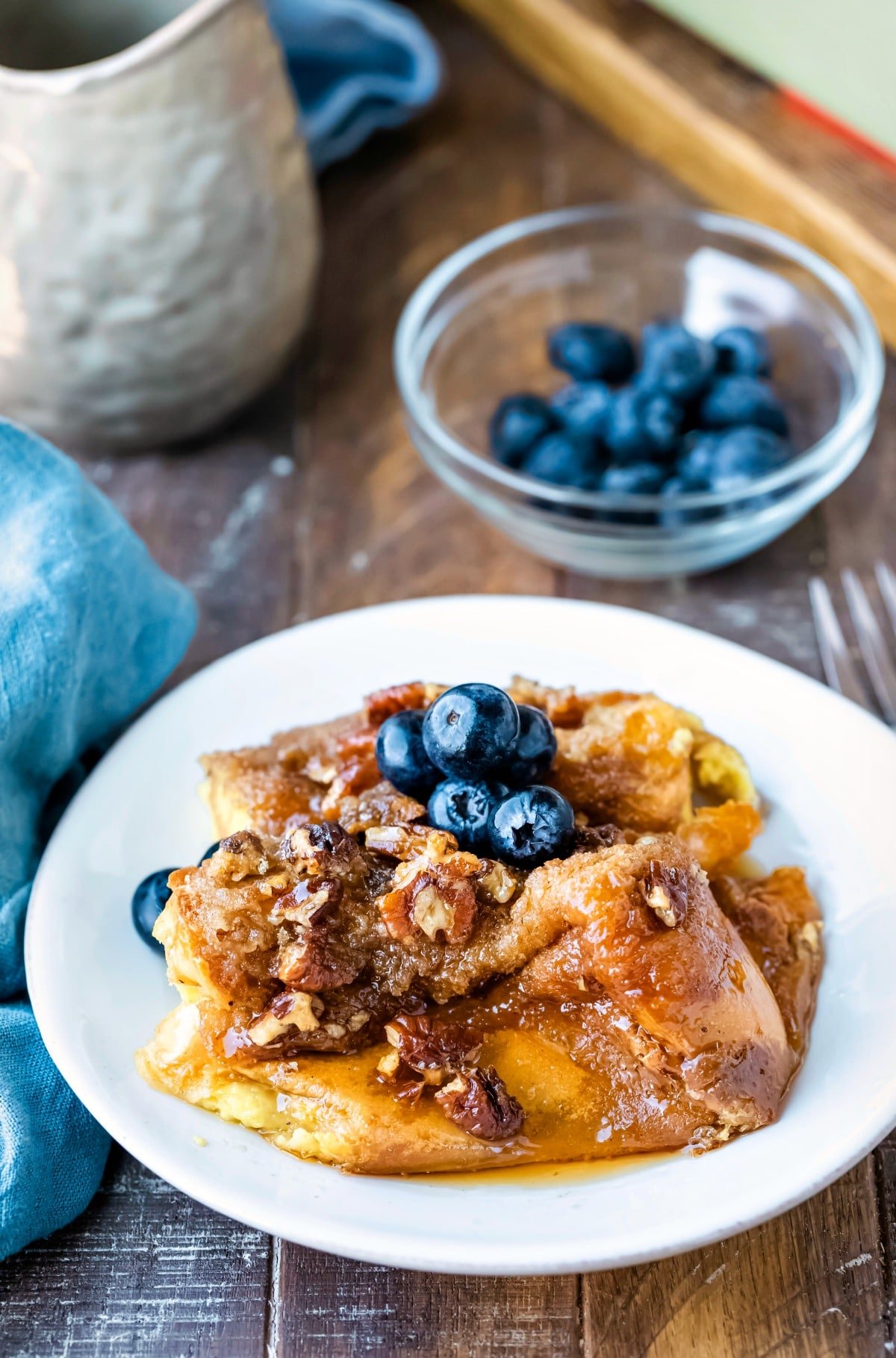 White plate of praline French toast topped with fresh blueberries