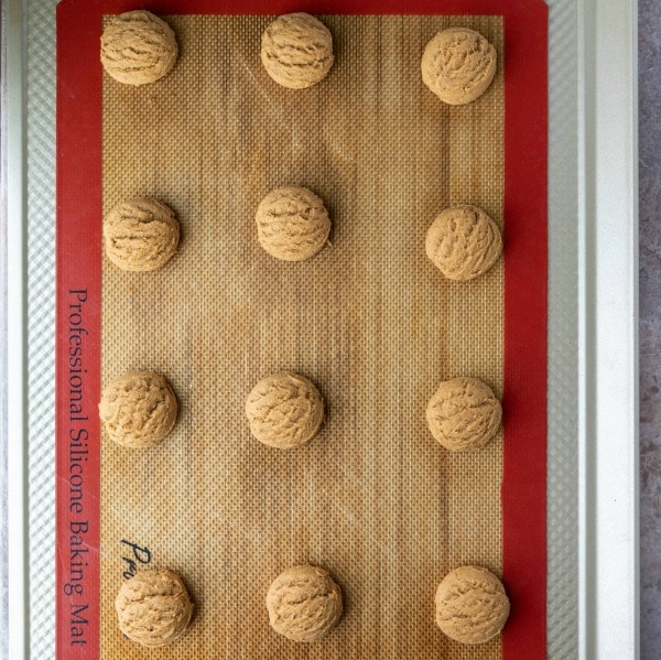 Baked pfeffernusse cookies on a silicone baking mat