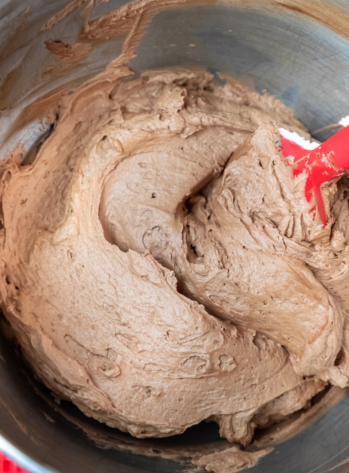 Chocolate buttercream frosting in a silver mixing bowl