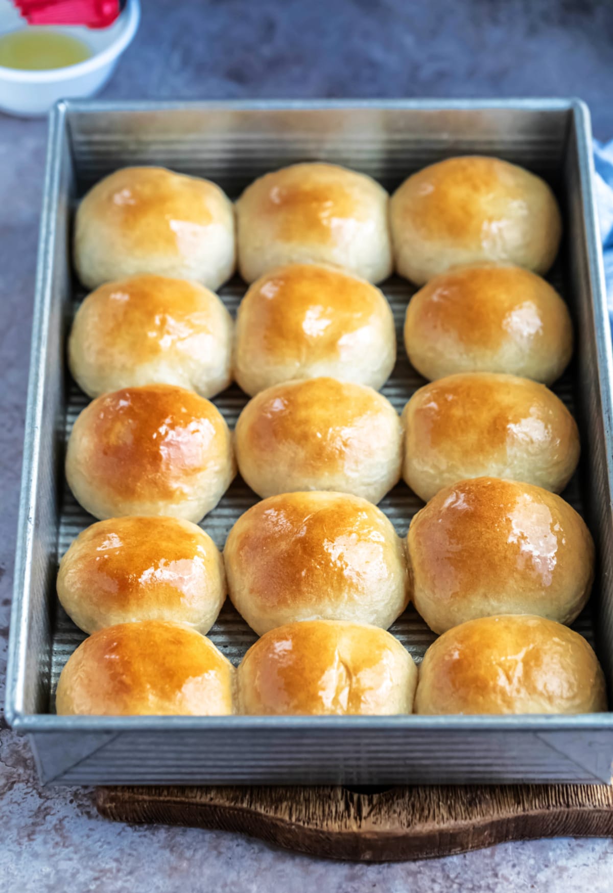 Pan of whole wheat dinner rolls on a wooden cutting board
