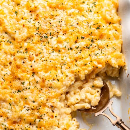 A spoon scooping up baked mac and cheese in a dish.