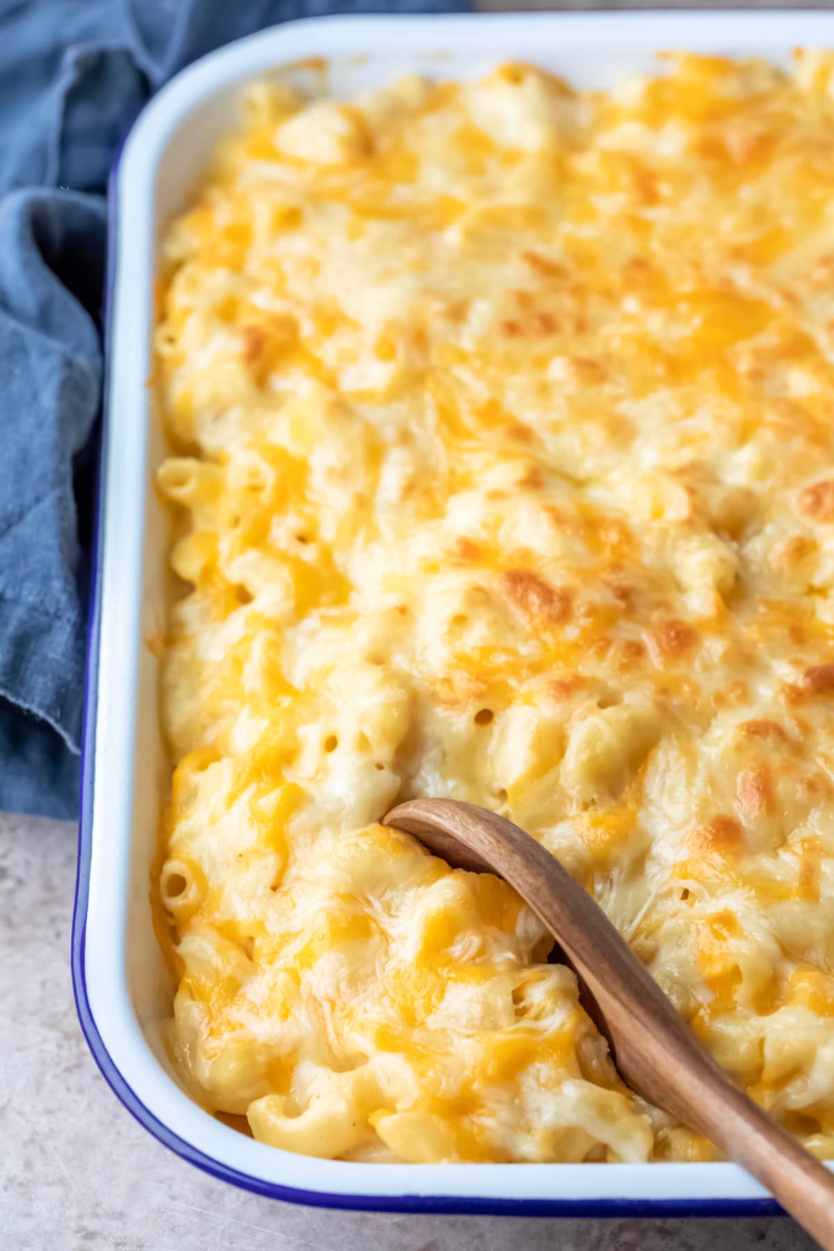 Wooden spoon in a pan of baked mac and cheese