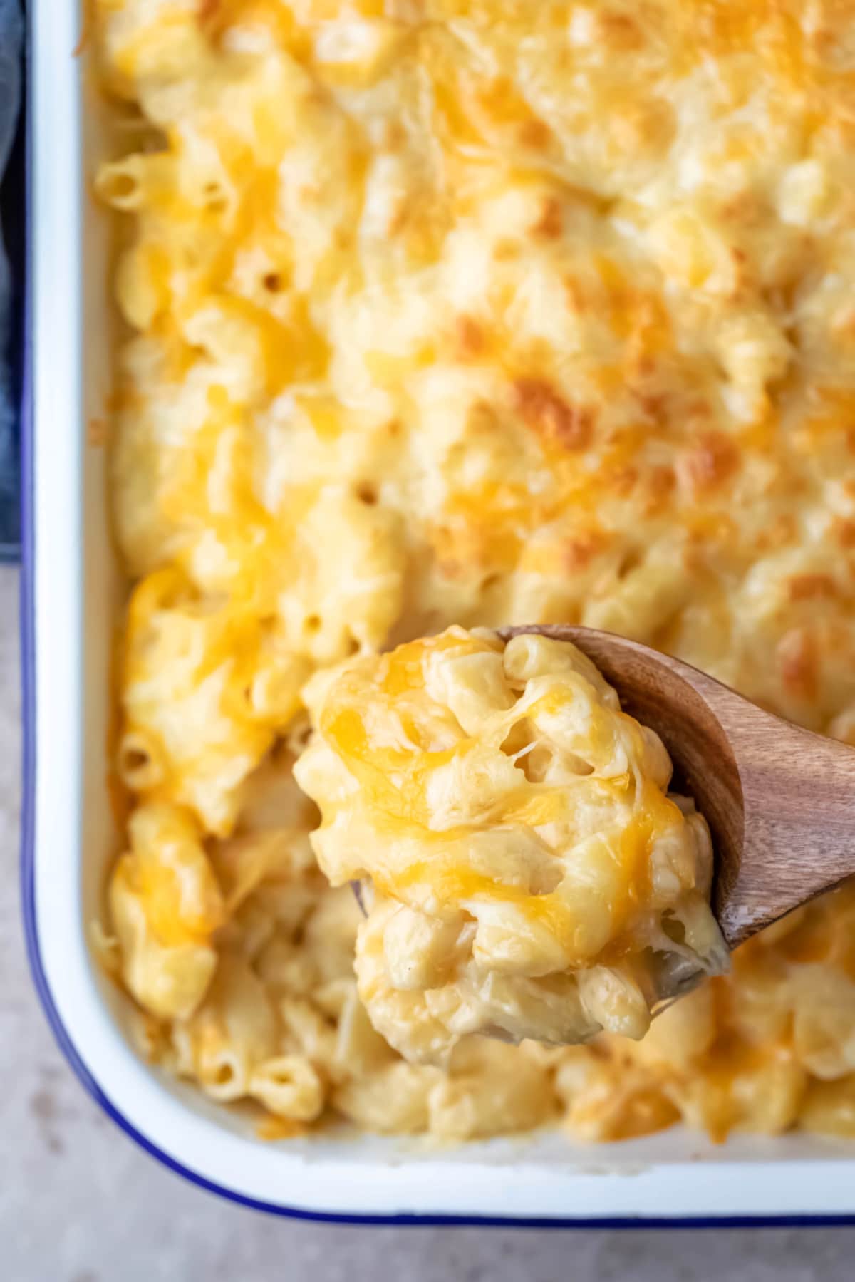 Wooden spoon scooping up baked mac and cheese