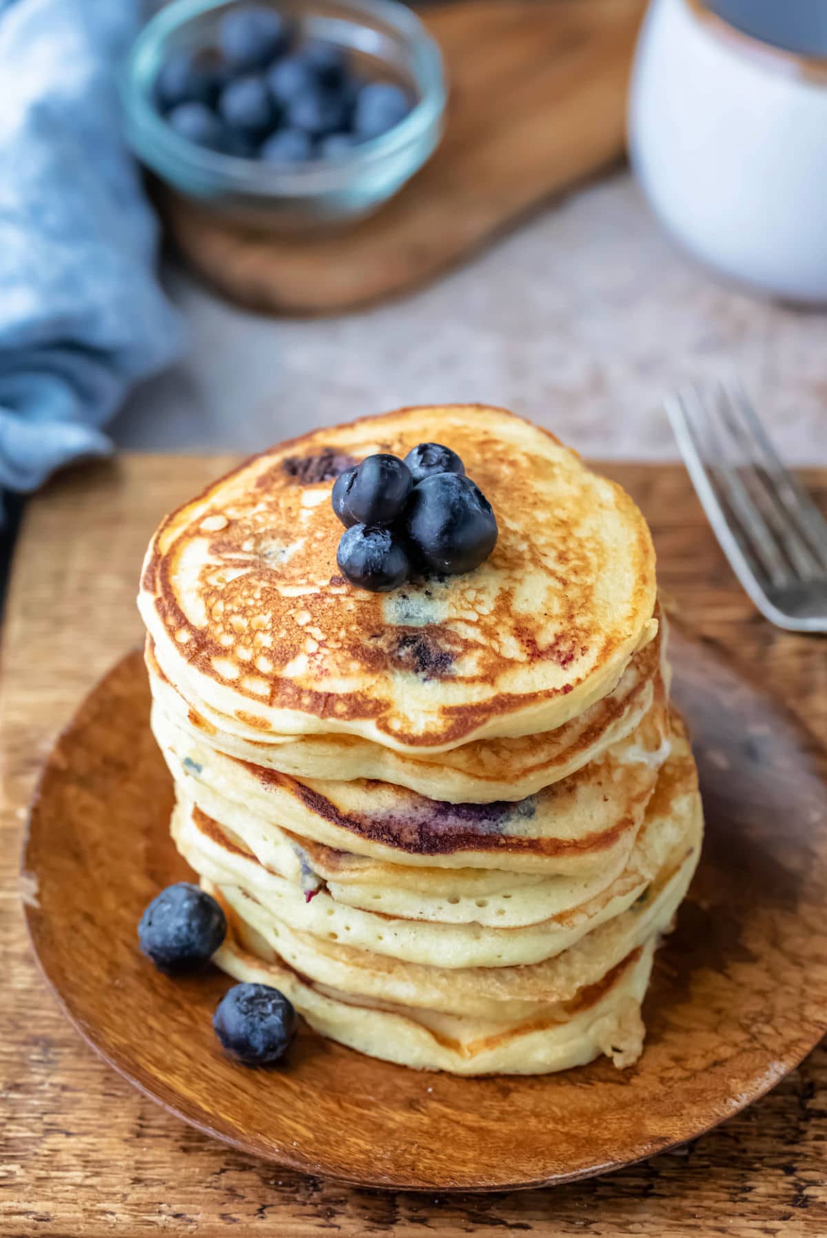 Stack of blueberry pancakes on a wooden plate