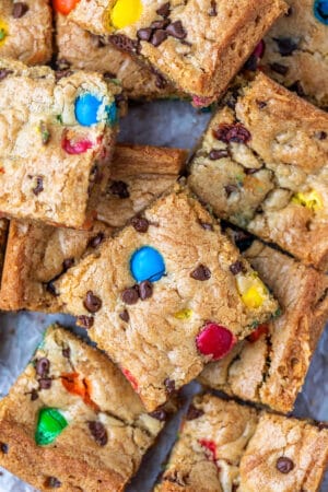 Stack of M&M cookie bars on a piece of parchment paper