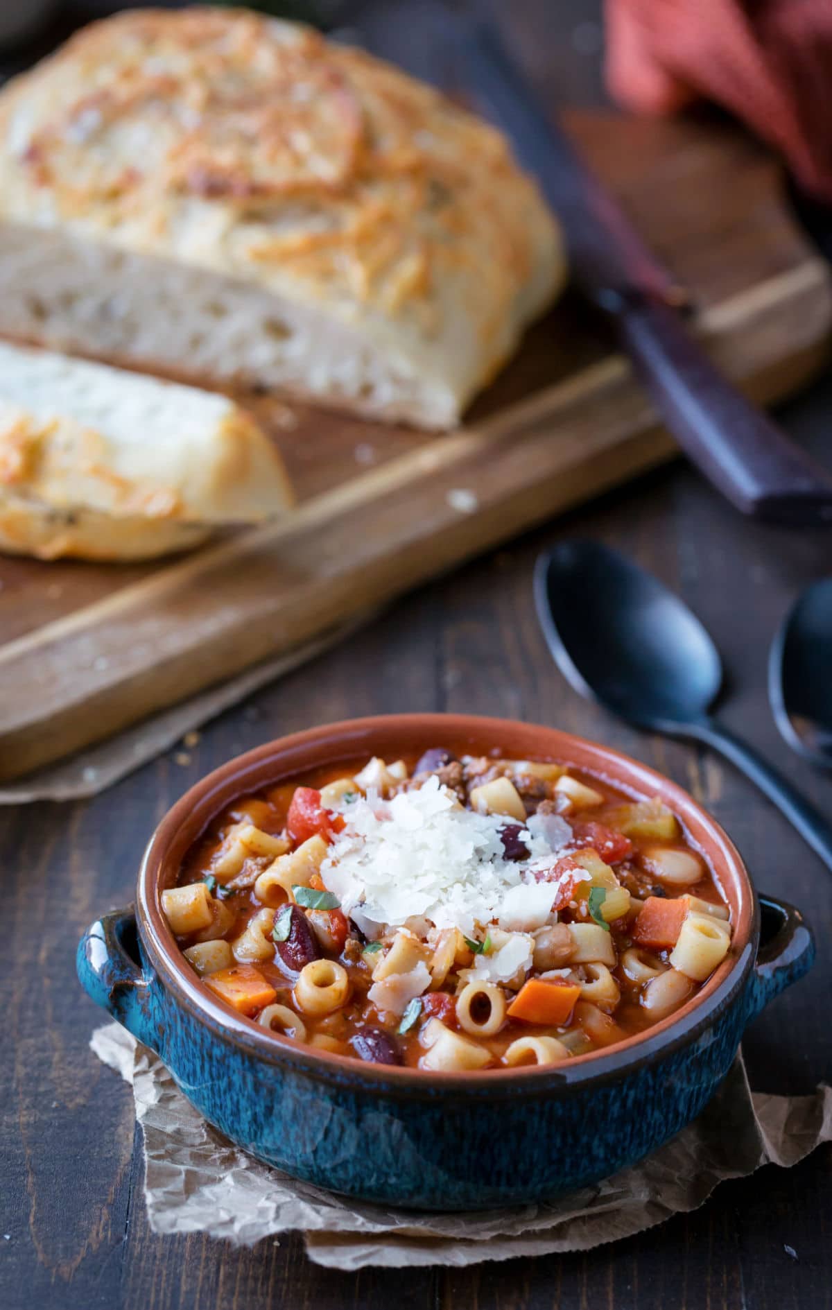 Bowl of pasta e fagioli soup next to a loaf of sliced bread