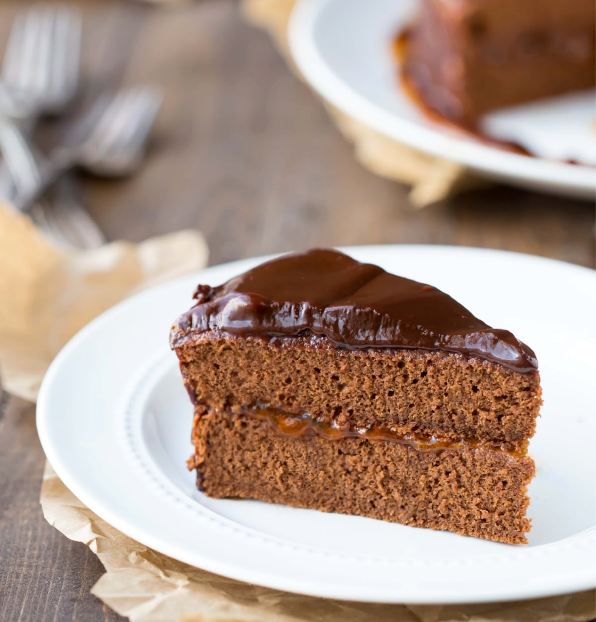 Sacher Torte slice on a white plate with cake behind it