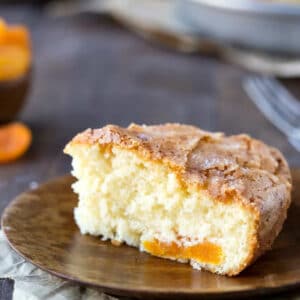 Slice of apricot cake on a wooden plate.