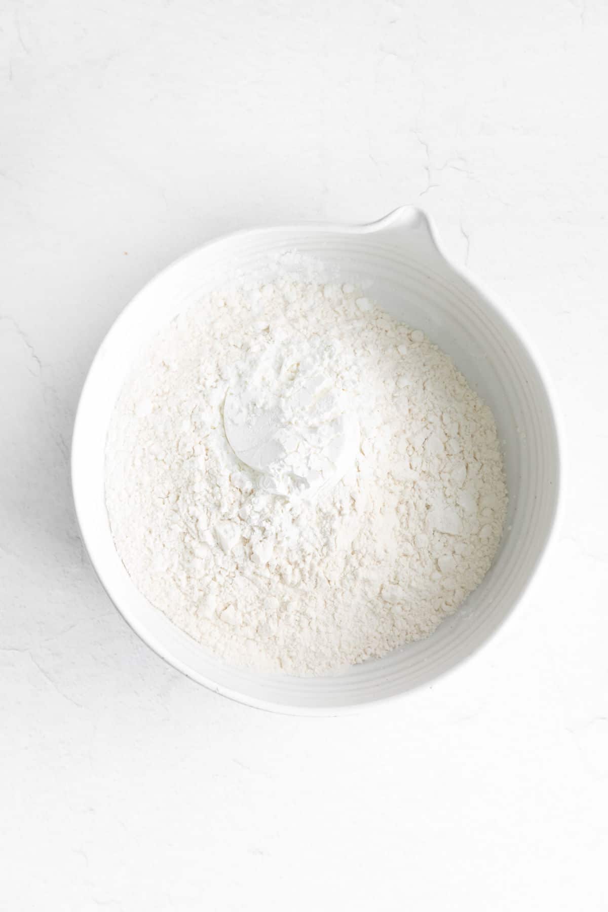 White mixing bowl filled with flour.