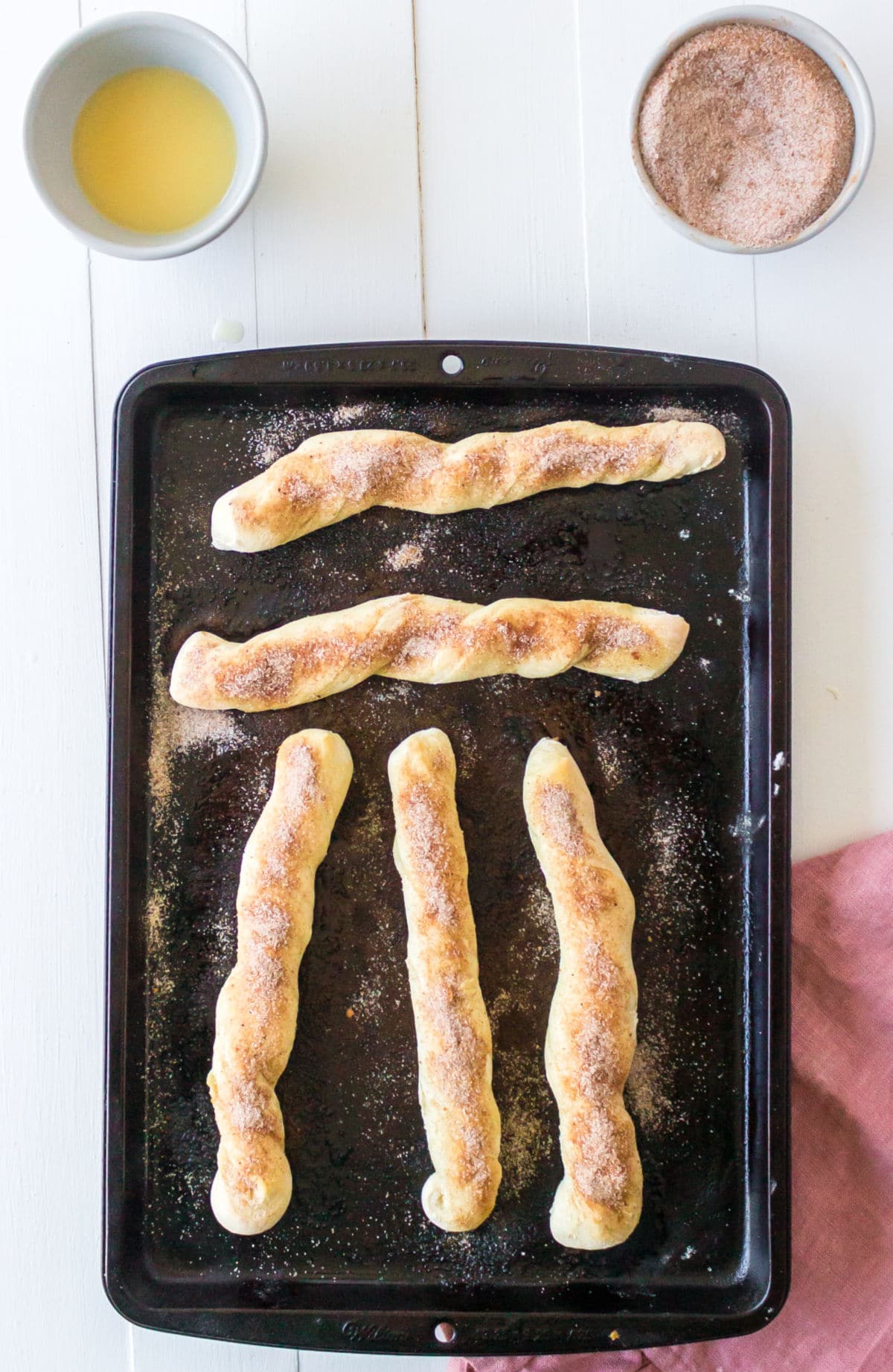 5 cinnamon sugar breadsticks on a metal baking pan.