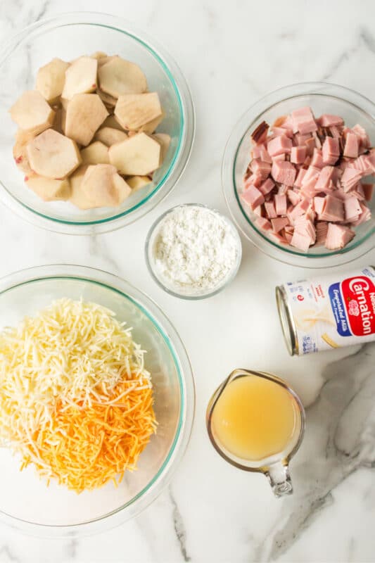 Slow cooker ham and potatoes ingredients in glass bowls.