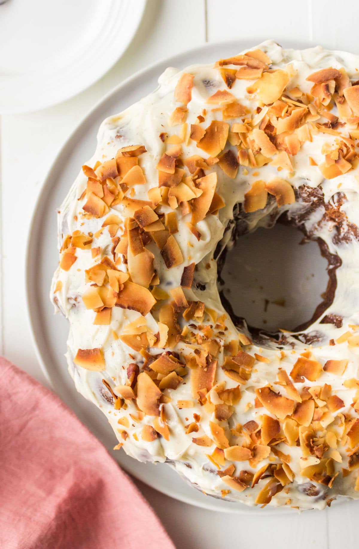 Hummingbird bundt cake topped with cream cheese frosting and toasted coconut.