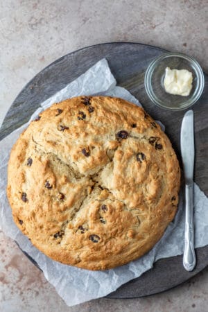 A loaf of Irish soda bread next to a knife and a dish of butter.