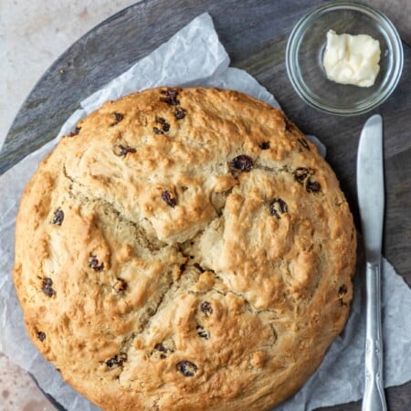 A loaf of Irish soda bread next to a knife and a dish of butter.