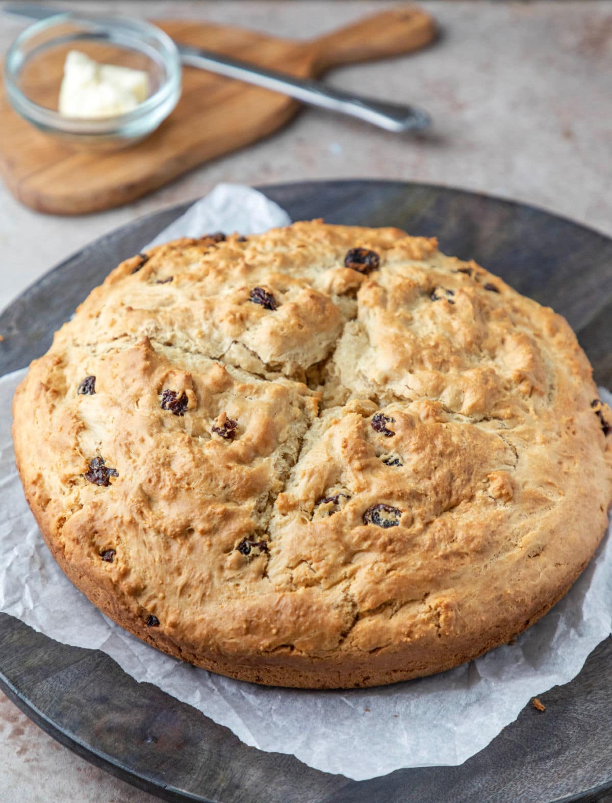 Irish soda bread on a round gray wood cutting board.