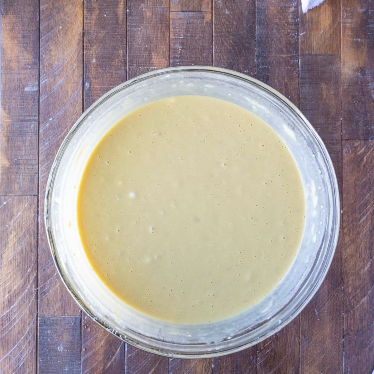 Yeast waffle batter in a glass mixing bowl.