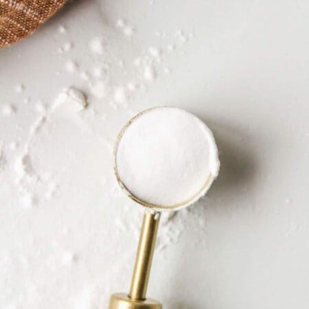 Wooden measuring spoon holding baking soda.
