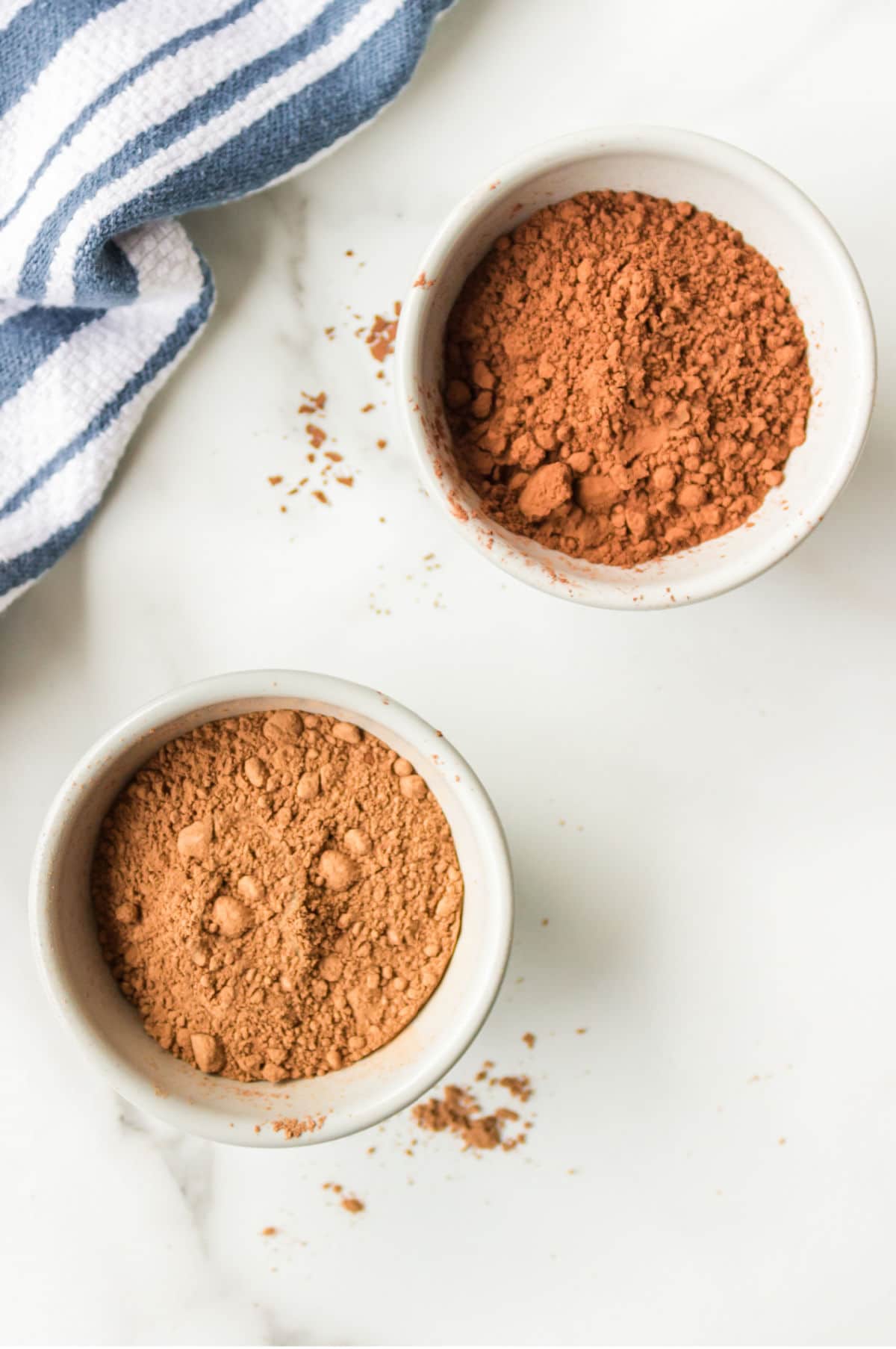 A dish of unsweetened cocoa powder next to a dish of Dutch-processed cocoa powder. 