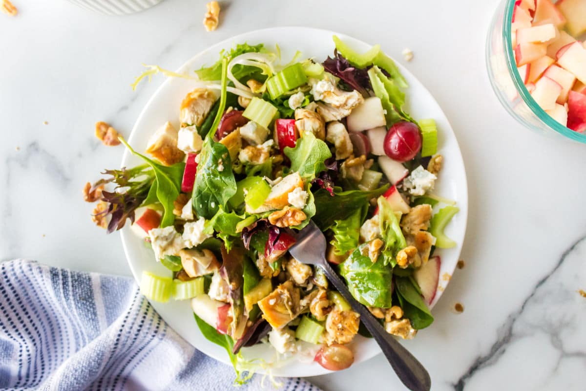 Waldorf salad on white plate with a silver fork in it. 