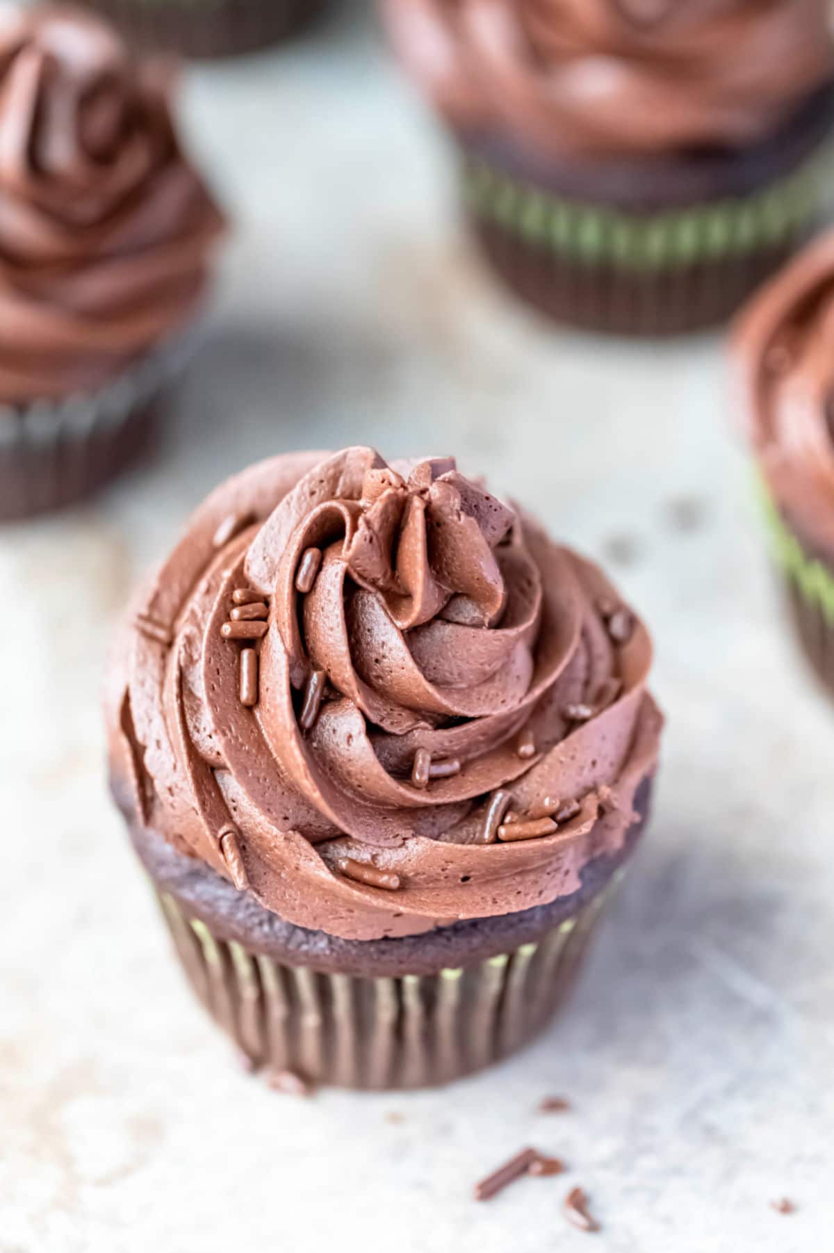 Close up photo of chocolate buttercream frosting topped with chocolate sprinkles. 