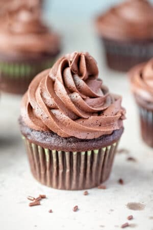 Chocolate cupcake with chocolate frosting next to chocolate sprinkles.