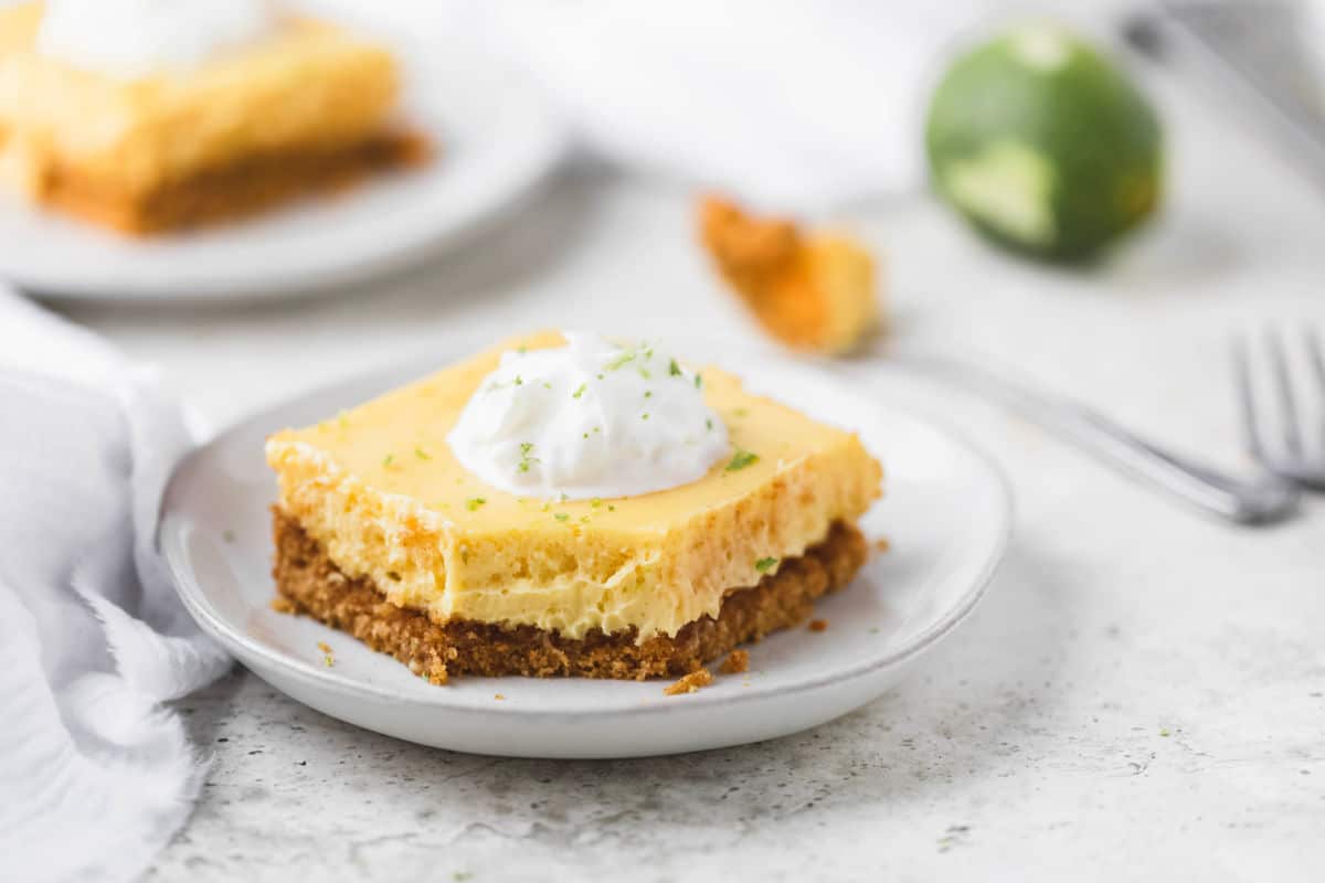 Key lime pie bar next to a fork with a bite of pie on it.