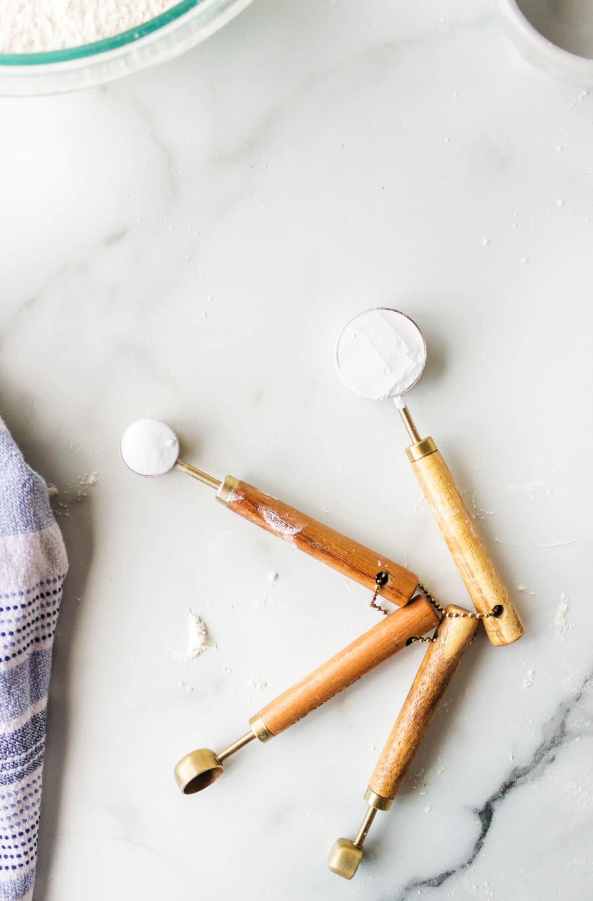 Measuring spoons with baking powder and baking soda on a marble background.