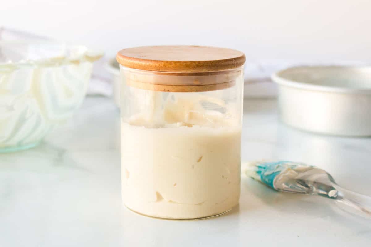 Glass jar filled with pan release next to a silicone pastry brush. 