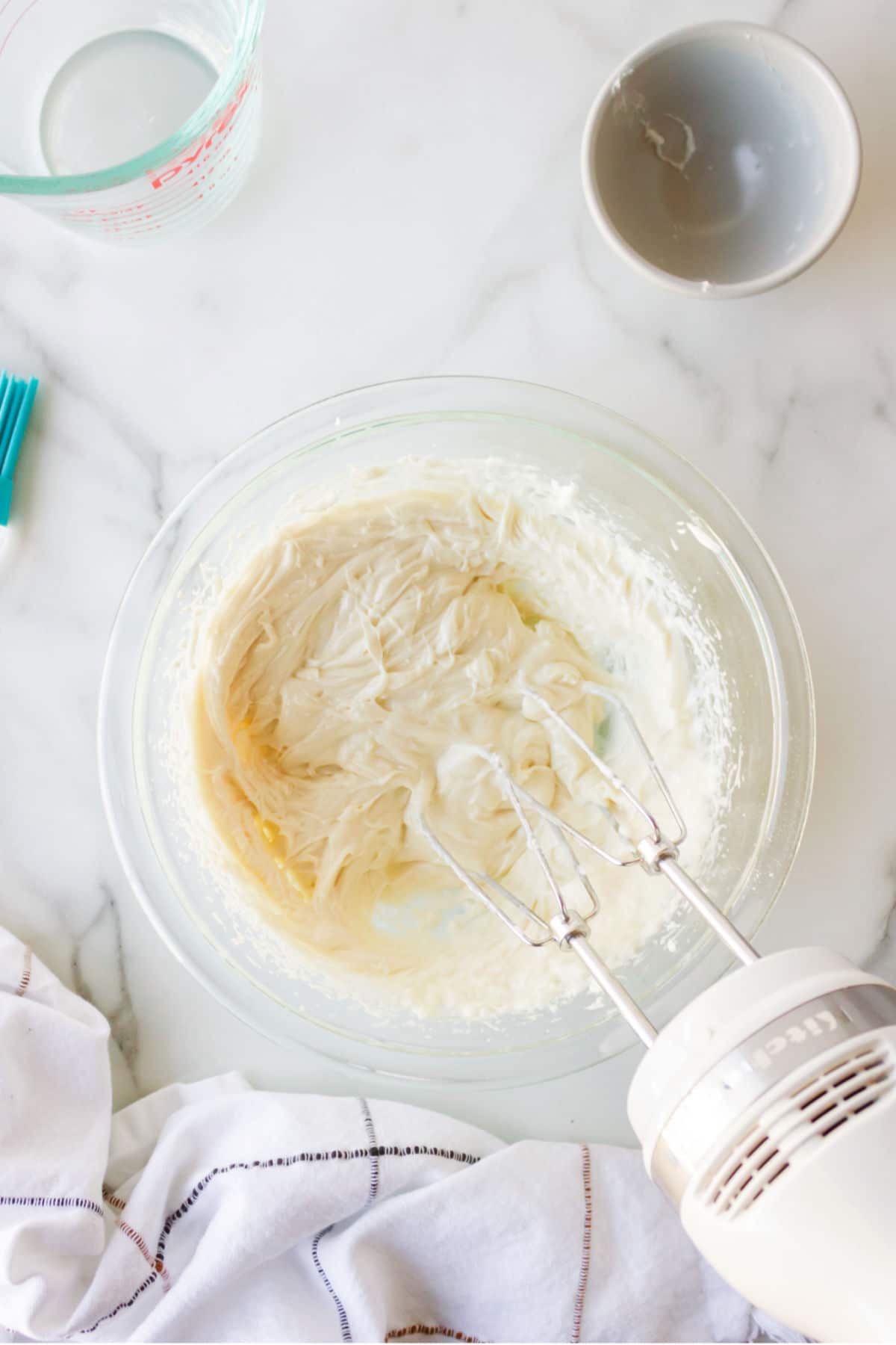 Hand mixer beating pan release ingredients together in a glass mixing bowl. 