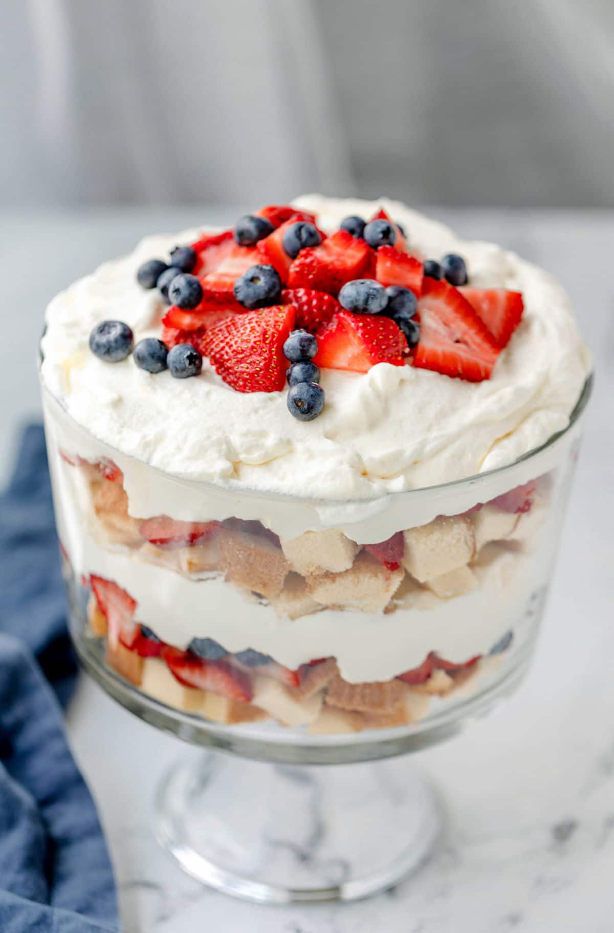 Trifle with layers of pound cake, berries, and whipped cream in a glass trifle dish.