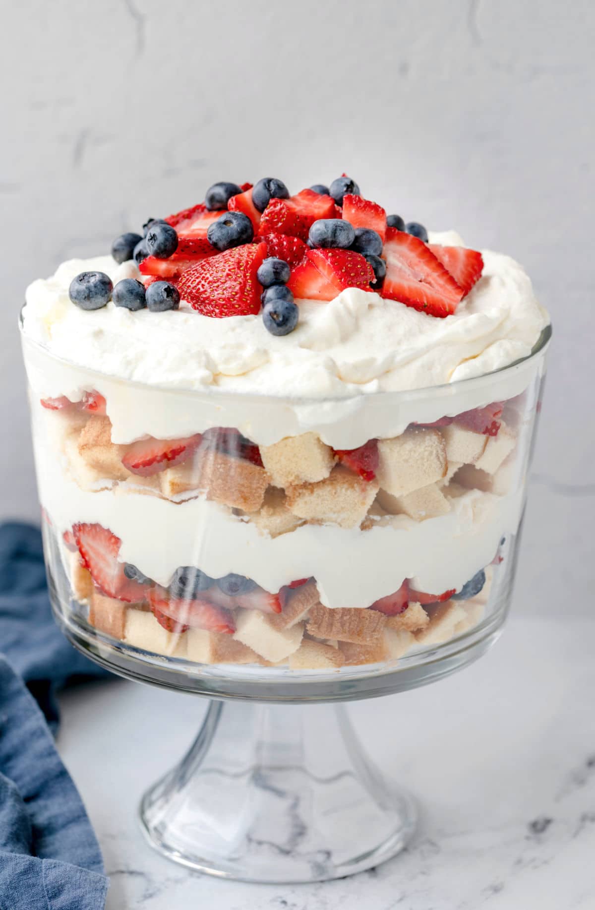 red white and blue trifle in a glass trifle dish on a marble background