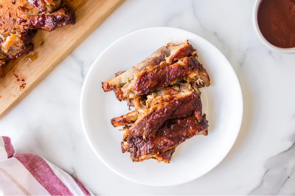 White plate piled with slow cooker ribs on it. 