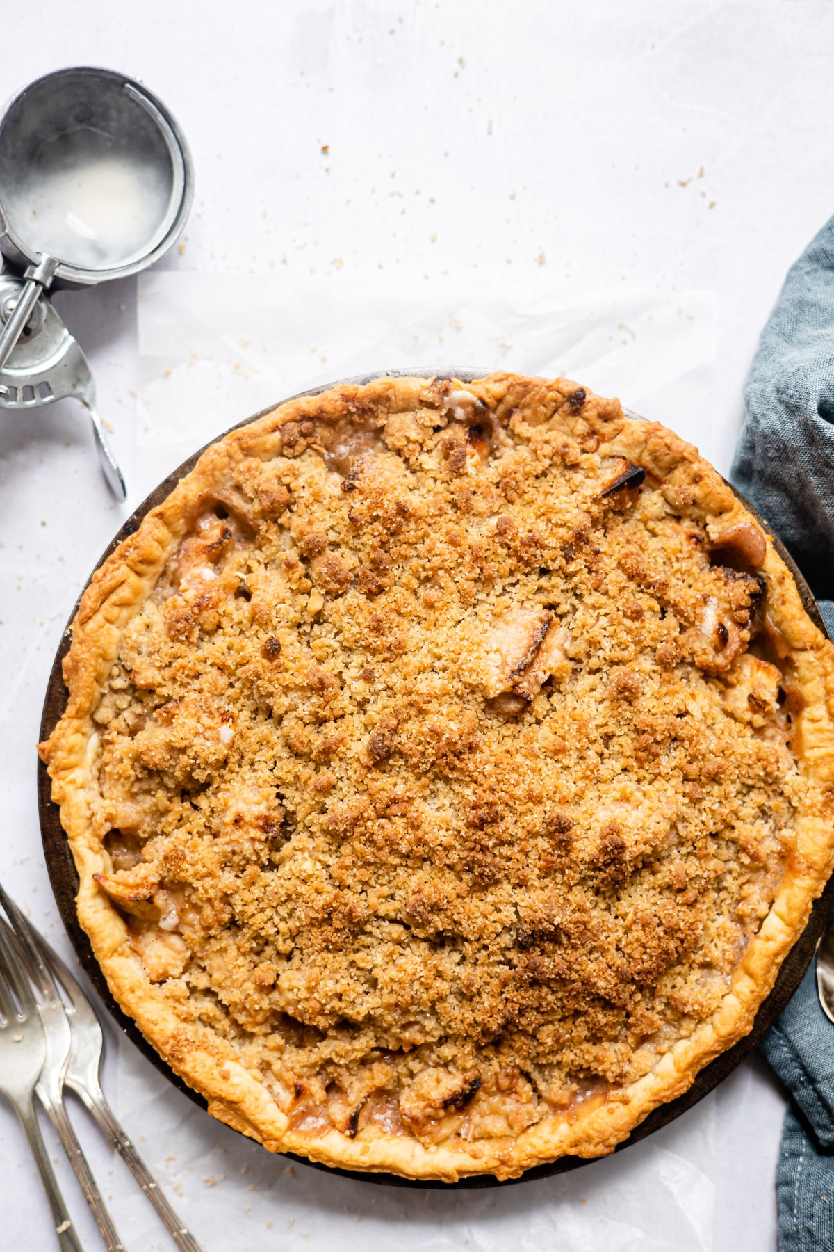 Baked apple crumb pie next to an ice cream scoop.