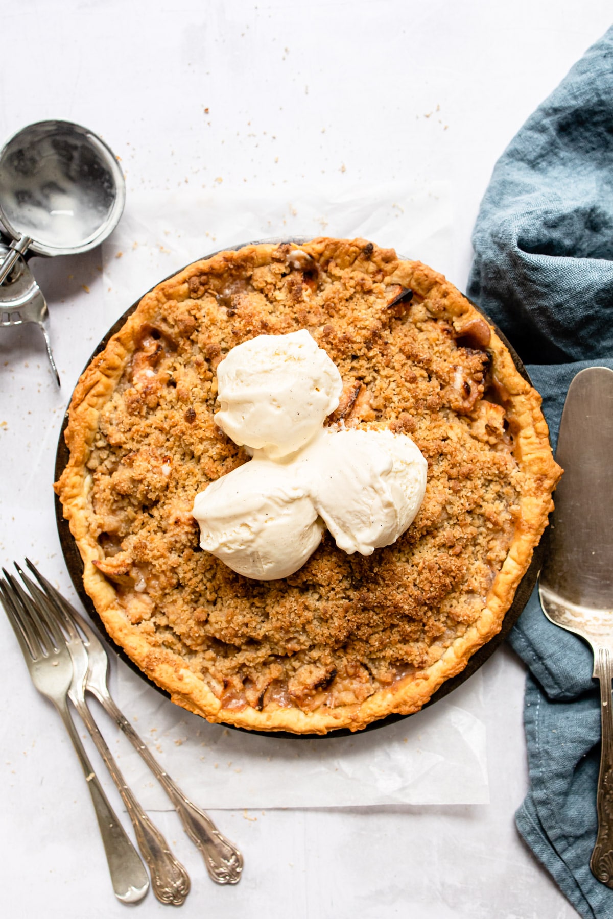 Three scoops of vanilla ice cream on an apple pie.