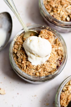 Cherry crisp in a glass ramekin topped with vanilla ice cream.