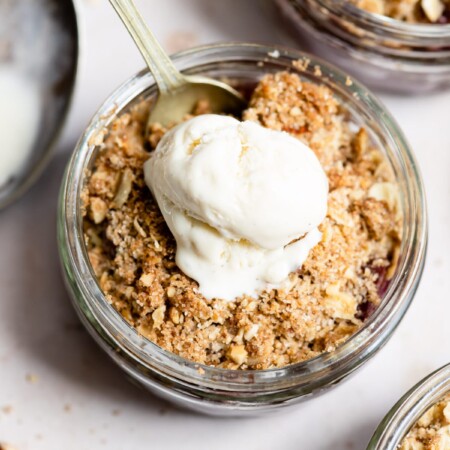 Cherry crisp in a glass ramekin topped with vanilla ice cream.