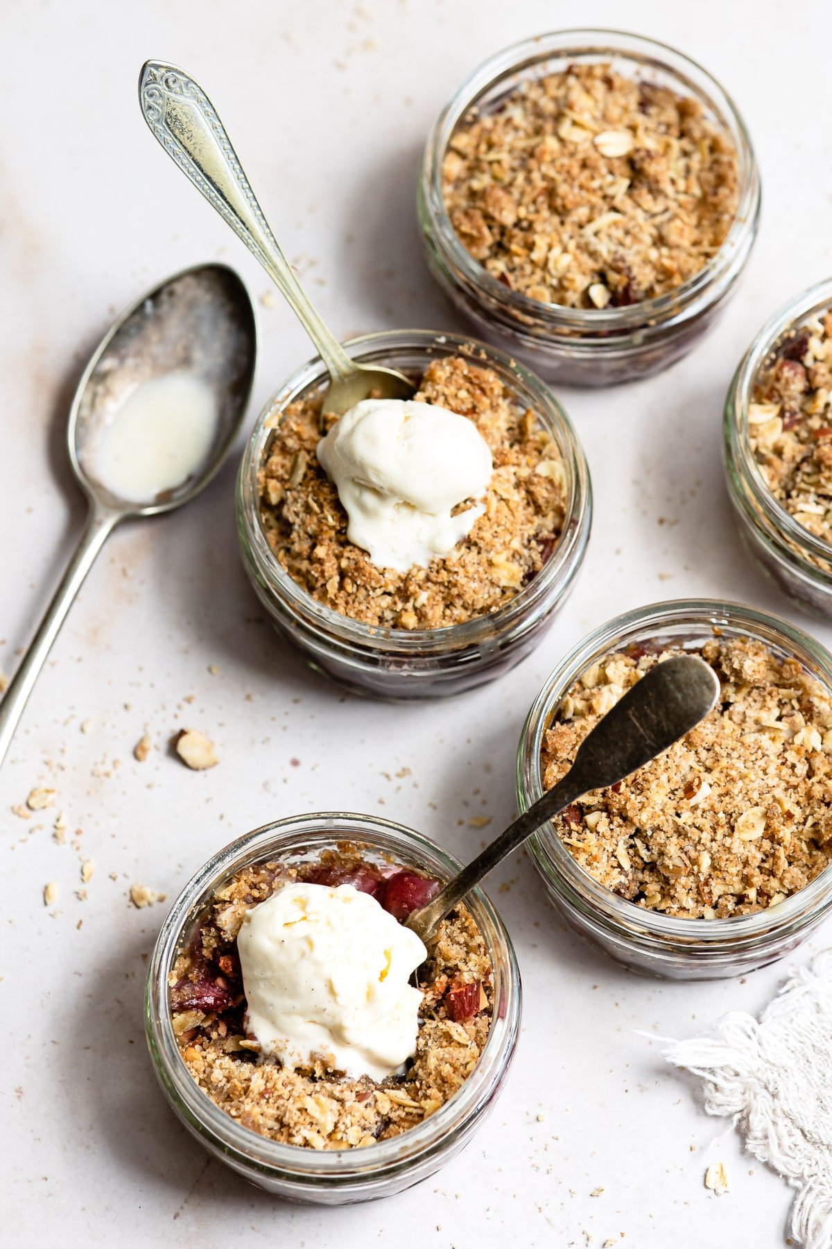 Two ramekins with cherry crisp topped with vanilla ice cream.