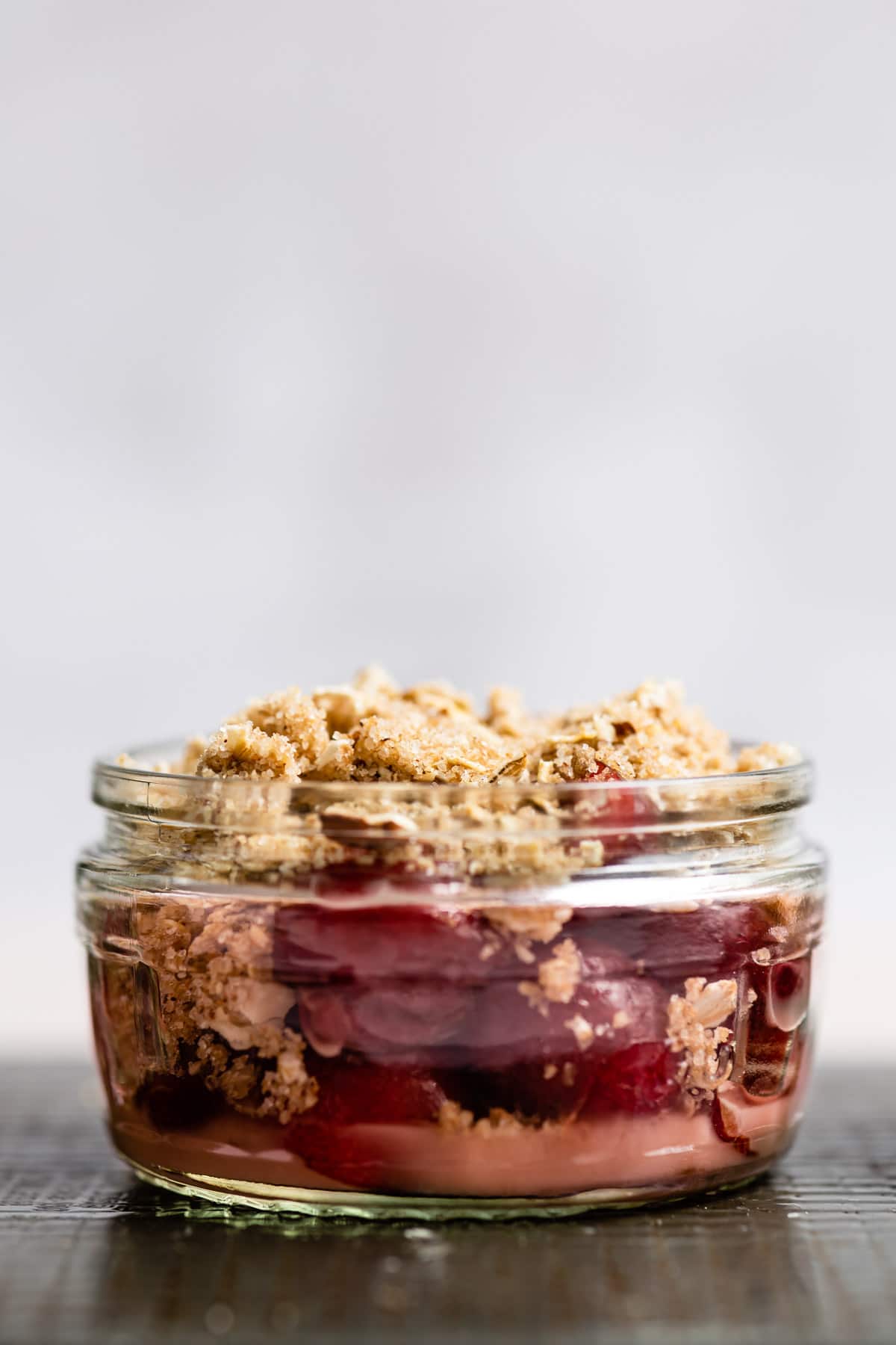 Close up photo of a cherry crisp in a glass jar.