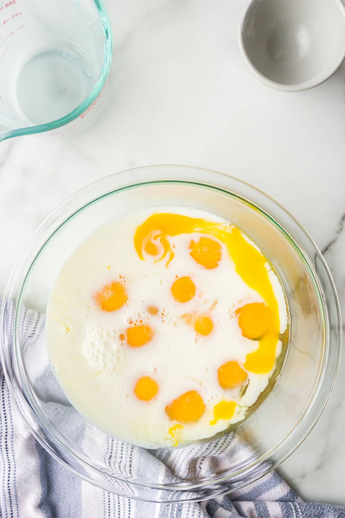 Eggs milk and sugar in a glass mixing bowl. 