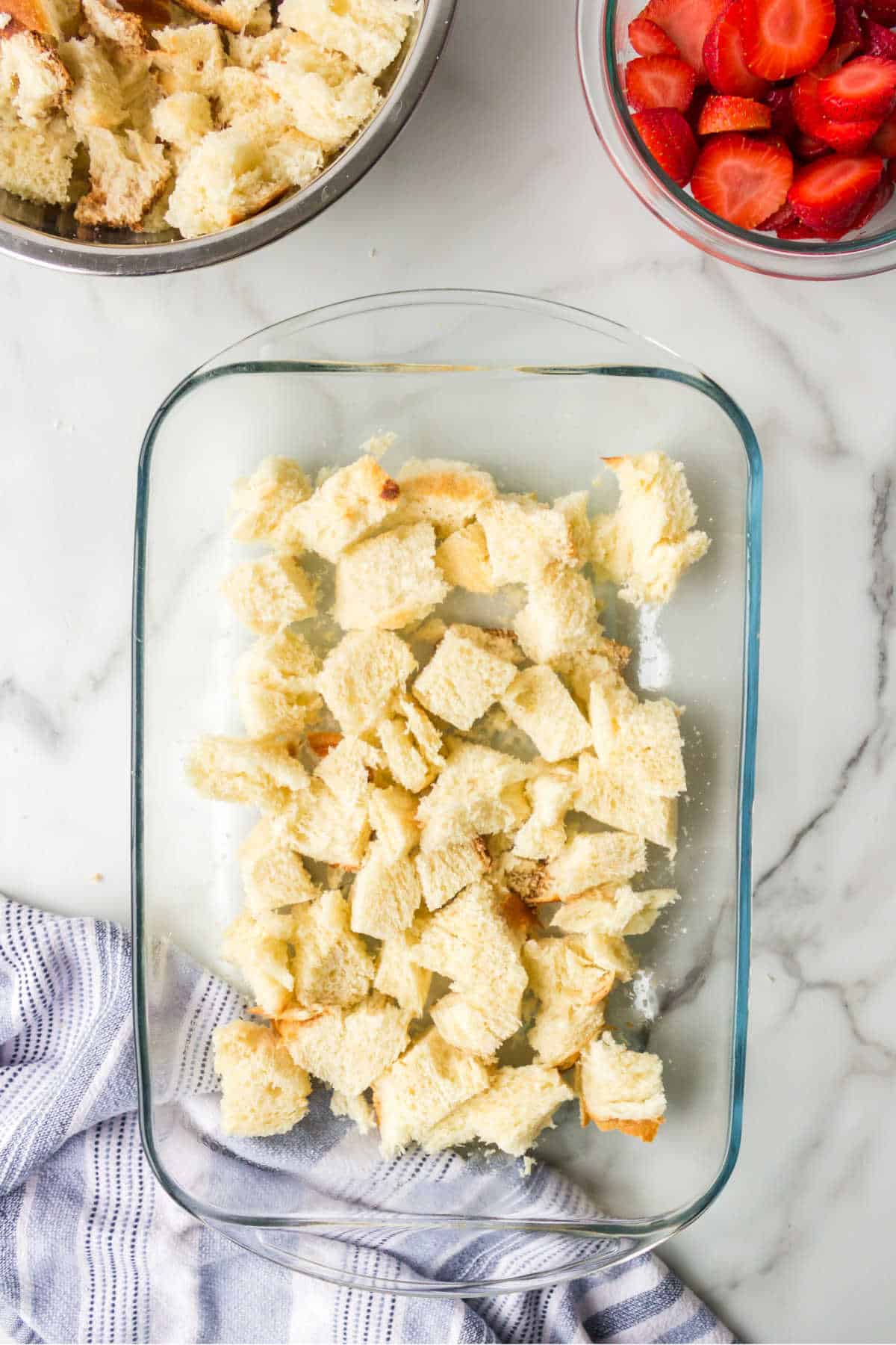 Bread cubes in the bottom of a glass baking dish. 