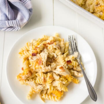 White plate with chicken bacon ranch pasta and a silver fork on it.